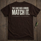 Dark brown t-shirt with white text: "THE LAKE HAS A MOOD. MATCH IT."