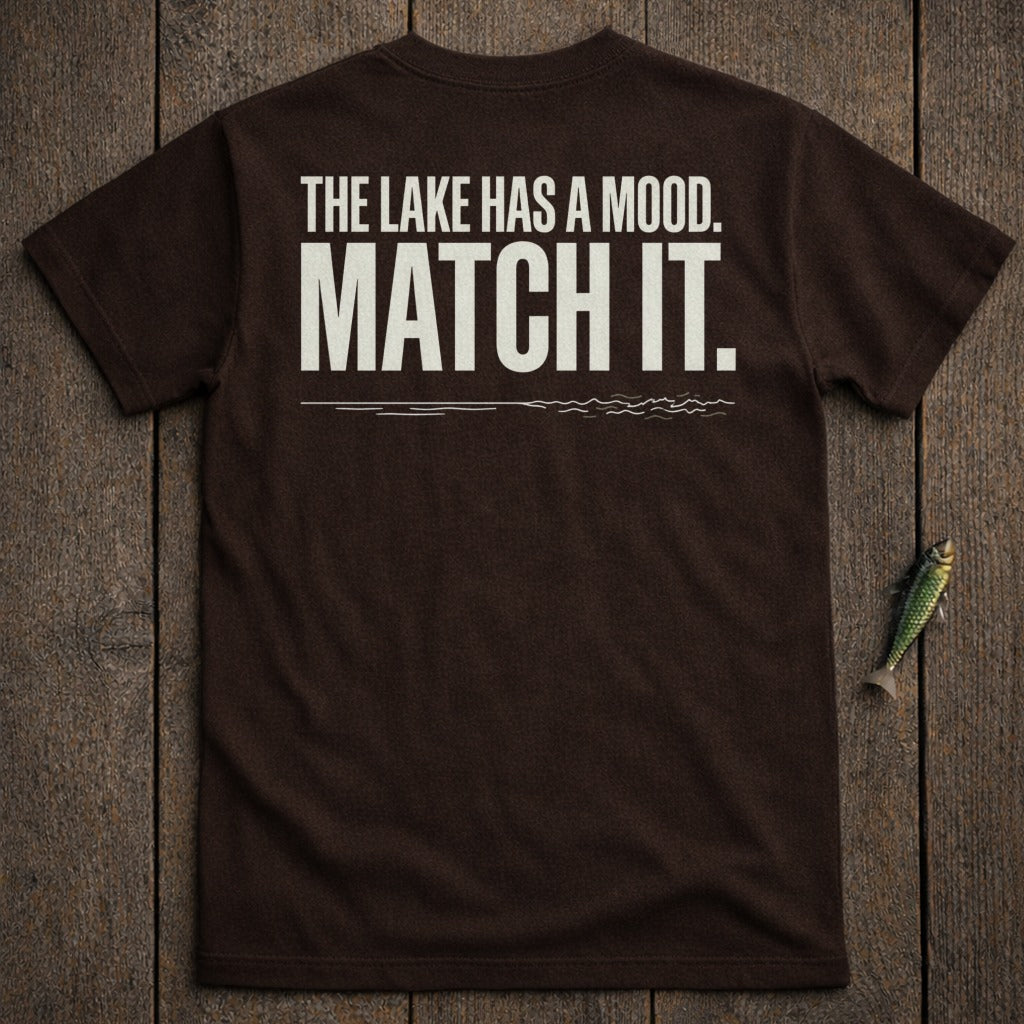 Dark brown t-shirt with white text: "THE LAKE HAS A MOOD. MATCH IT."