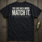 Black t-shirt with white text "THE LAKE HAS A MOOD. MATCH IT." and a small fish.