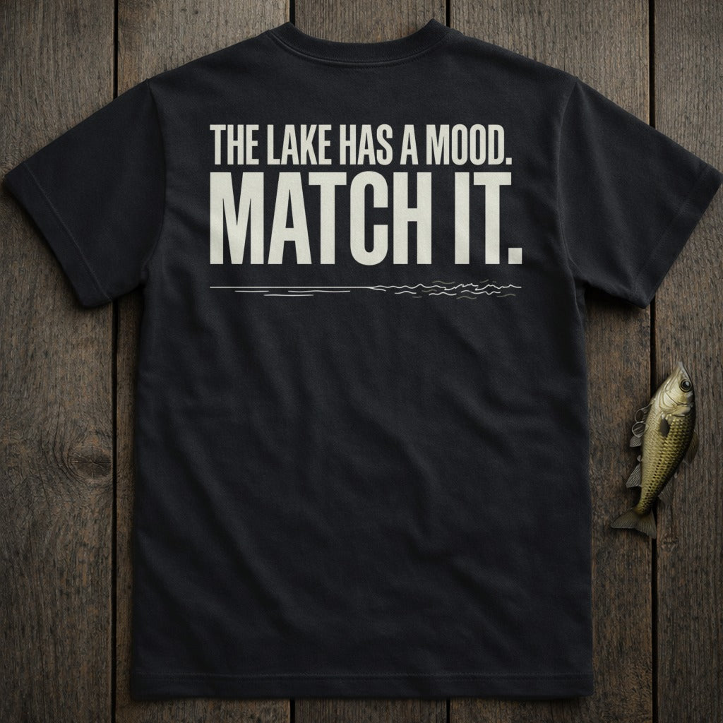 Black t-shirt with white text "THE LAKE HAS A MOOD. MATCH IT." and a small fish.
