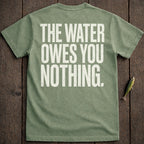 Green t-shirt with "THE WATER OWES YOU NOTHING" text, on wooden background.