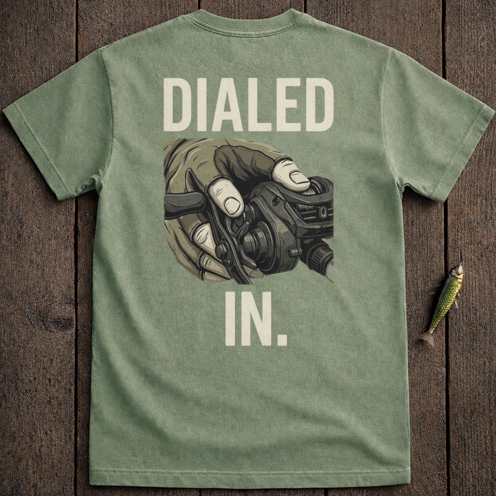 Green t-shirt with "DIALED IN." and illustration of a hand holding a fishing reel.