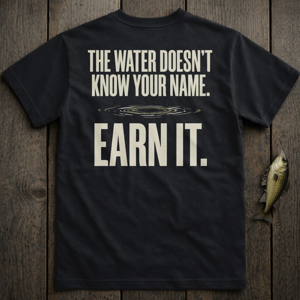 Black t-shirt with text "THE WATER DOESN'T KNOW YOUR NAME. EARN IT."