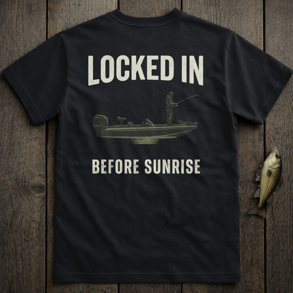 Black t-shirt with graphic of angler in boat, text "LOCKED IN BEFORE SUNRISE".