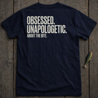 Navy t-shirt with white text "OBSESSED. UNAPOLOGETIC. ABOUT THE BITE."
